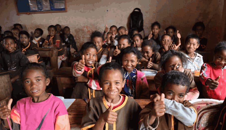 Enfants souriants levant le pouce dans une salle de classe